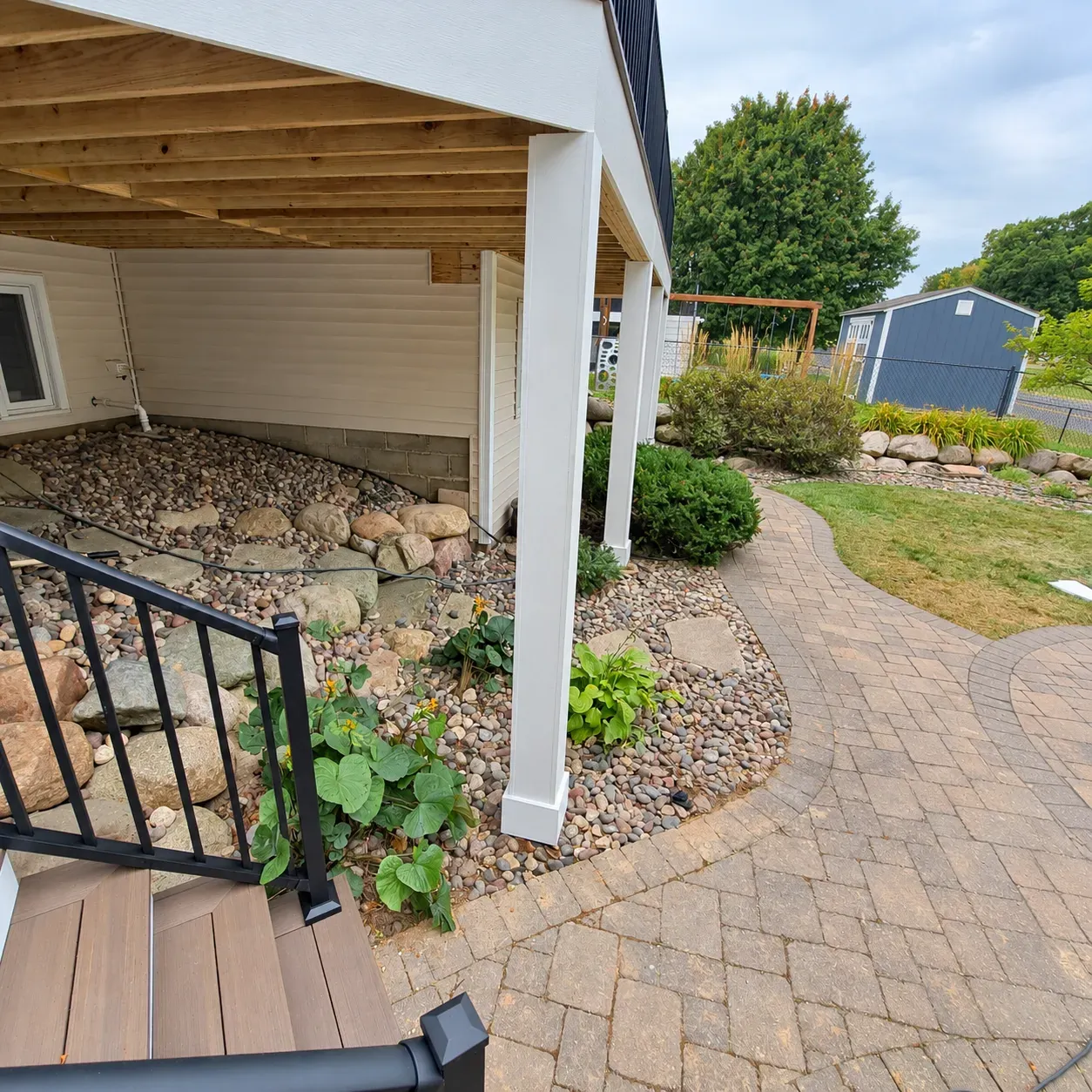 Open area beneath the rebuilt Eagan deck with wrapped white posts and paver walkway