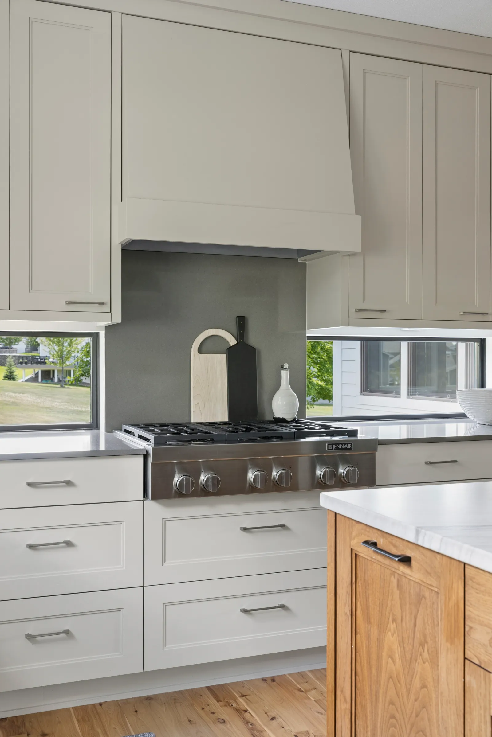 Full-overlay cabinetry surrounding a Jenn-Air range with jamb-free Pella windows in a Lakeville kitchen remodel