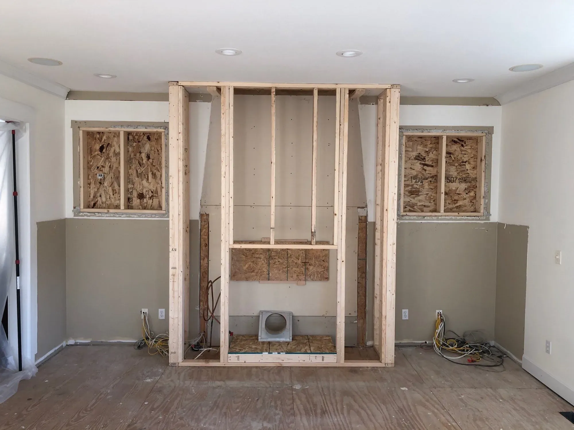 Construction-stage view of a Lakeville living room wall before the fireplace and cabinetry remodel