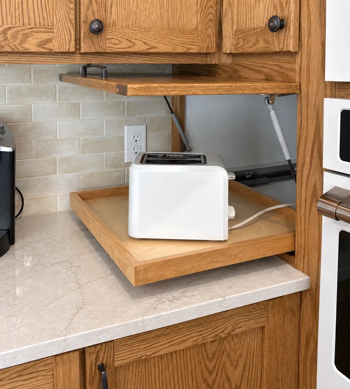 Red-oak appliance garage with a pull-out tray holding a toaster in a Lakeville kitchen remodel