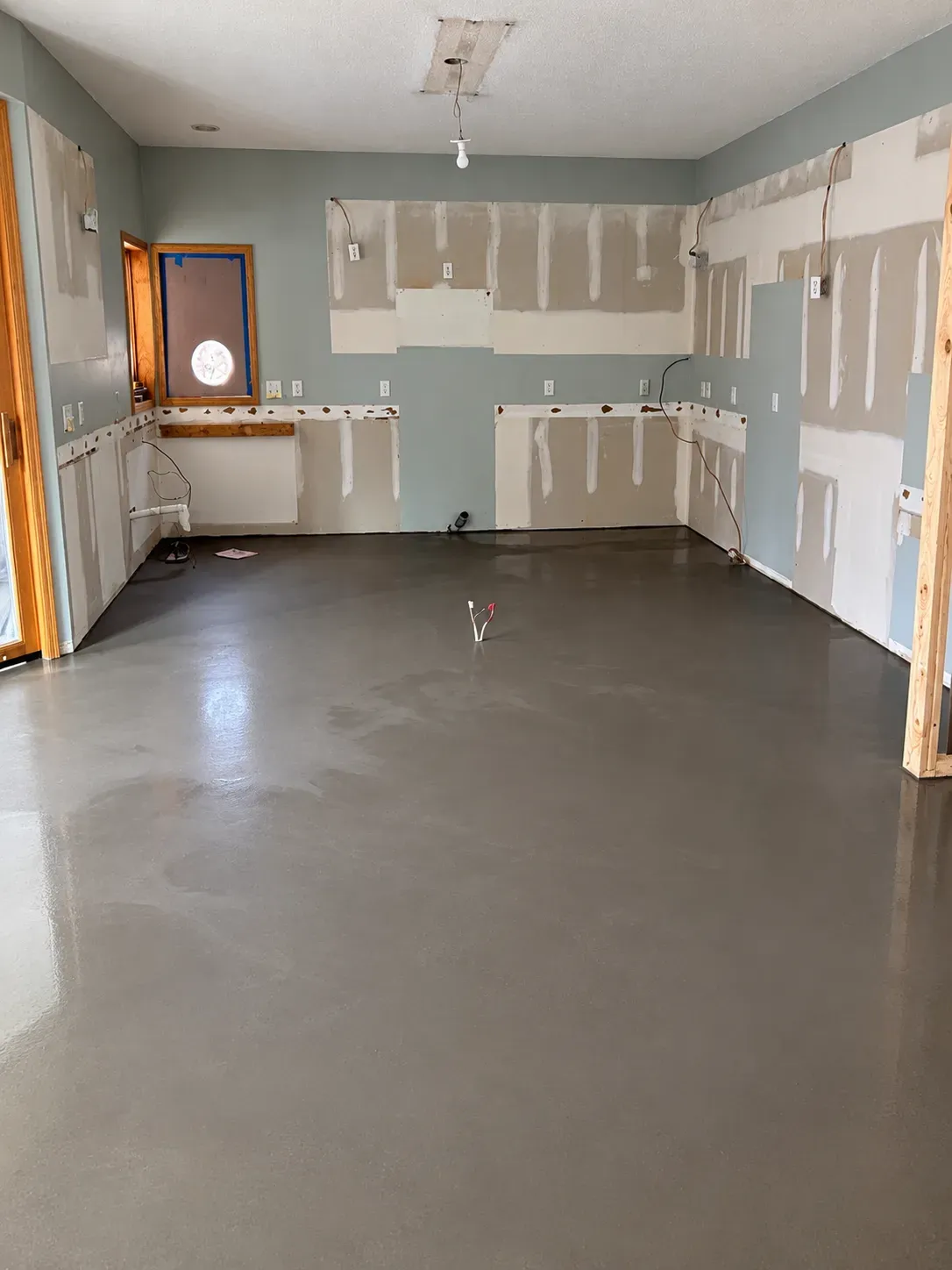 Self-leveling concrete poured over the kitchen subfloor after tile demolition in a Lakeville kitchen remodel