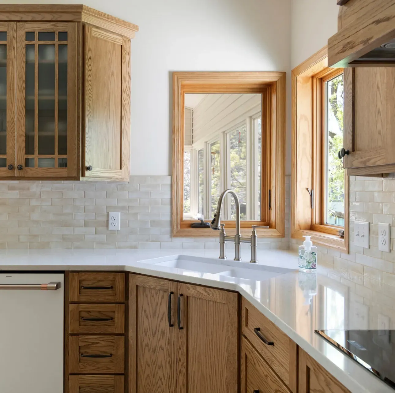 Corner sink with a white Elkay sink, brushed-gold Kraus faucet, Lumataj quartz and Coco Canvas porcelain backsplash in a Lakeville kitchen remodel