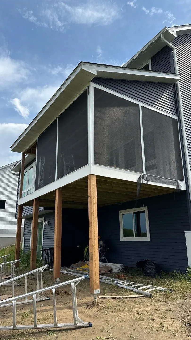 A screen porch addition in Lakeville supported on cedar posts over a walkout, with a shed roof tied into the house siding
