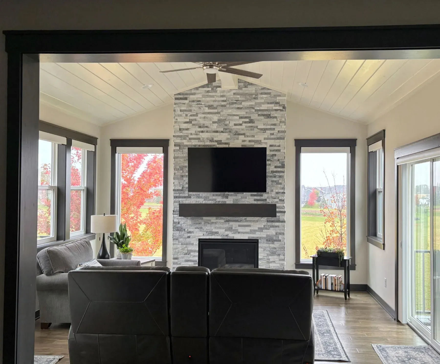View from the house into a Lakeville four-season porch with a stone fireplace and vaulted ceiling