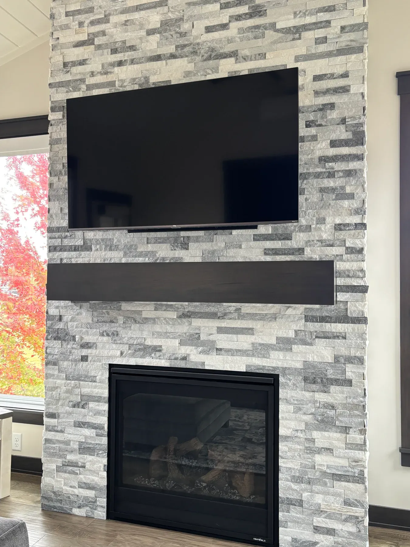Close-up of the gray and white stacked stone fireplace with a dark wood mantel in the Lakeville porch