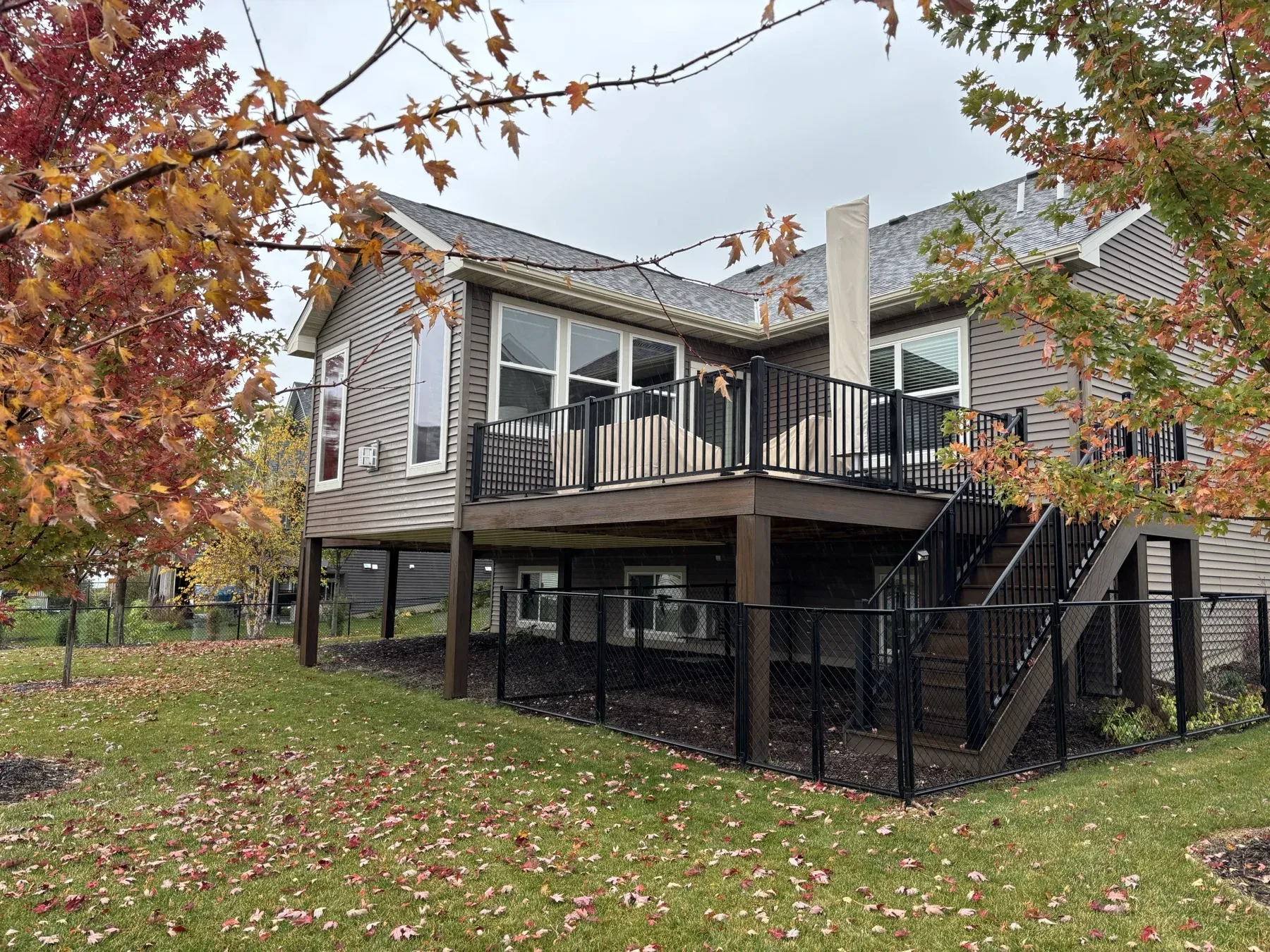 Lakeville four-season porch and seating deck with stairs, framed by fall maple trees