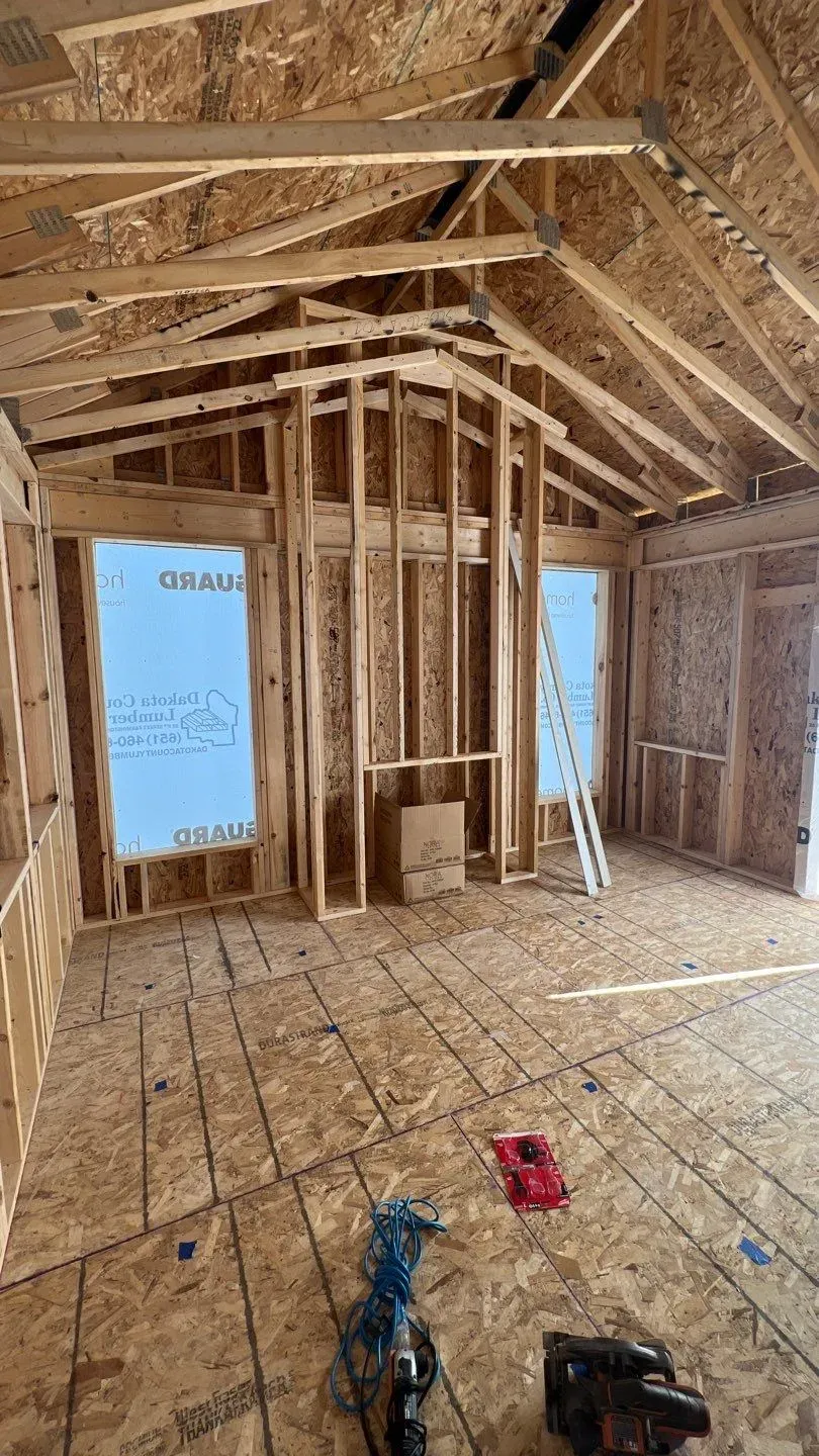 Framed walls and vaulted ceiling of the Lakeville four-season porch, with the fireplace wall framed between two window openings