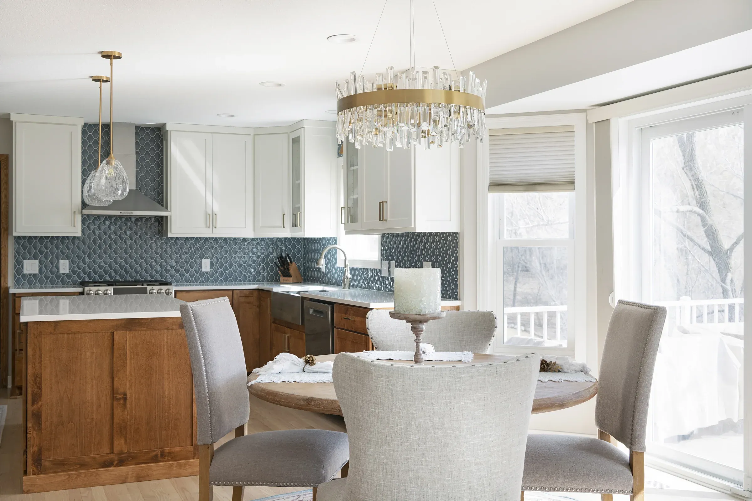 Open-concept kitchen and dining area after main-level remodel in Elko New Market, MN – hardwood floors, brass chandelier, and blue-green tile backsplash