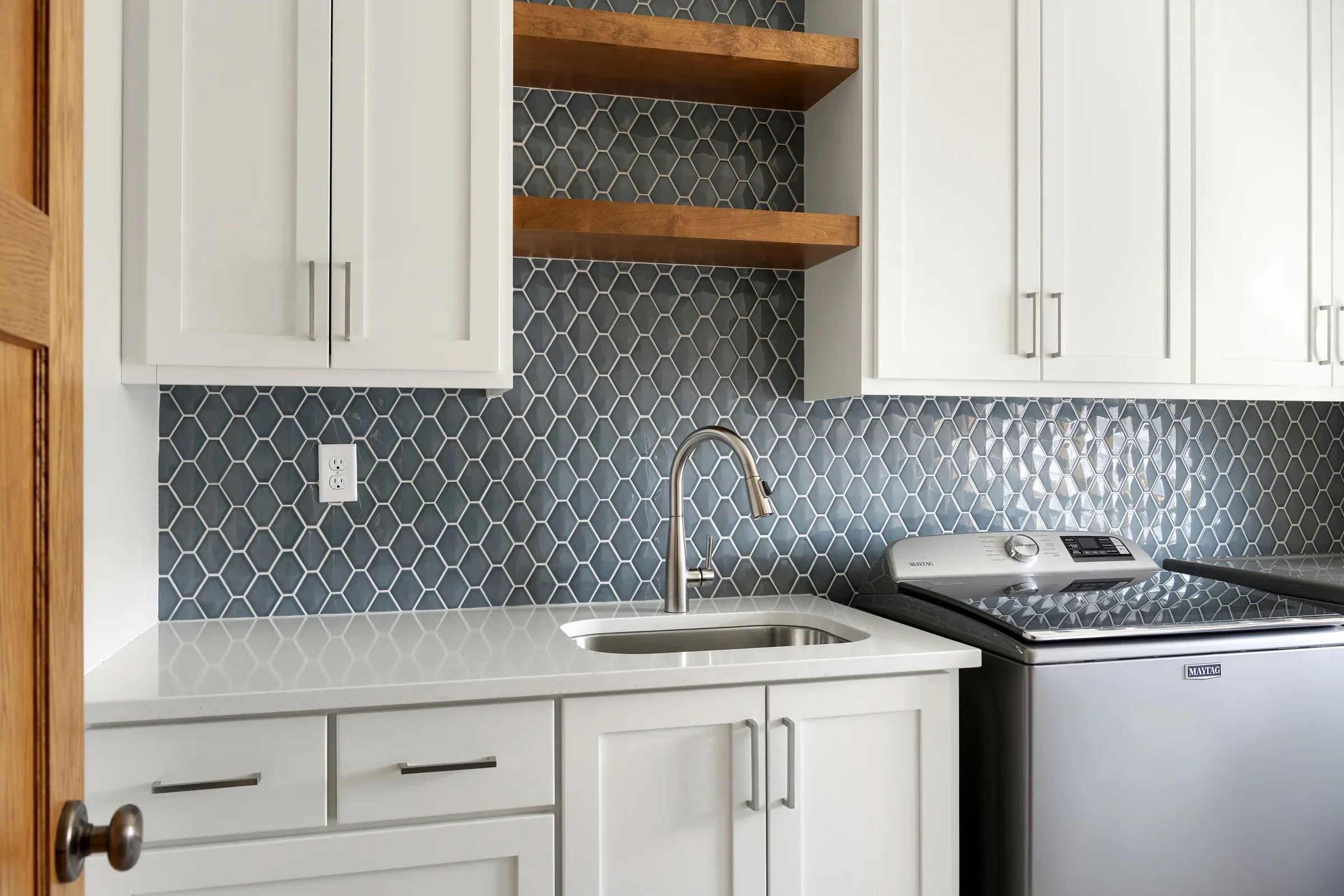 Laundry room remodel with quartz counters, open wood shelving, blue-green tile backsplash, and LVP flooring – Elko New Market, MN