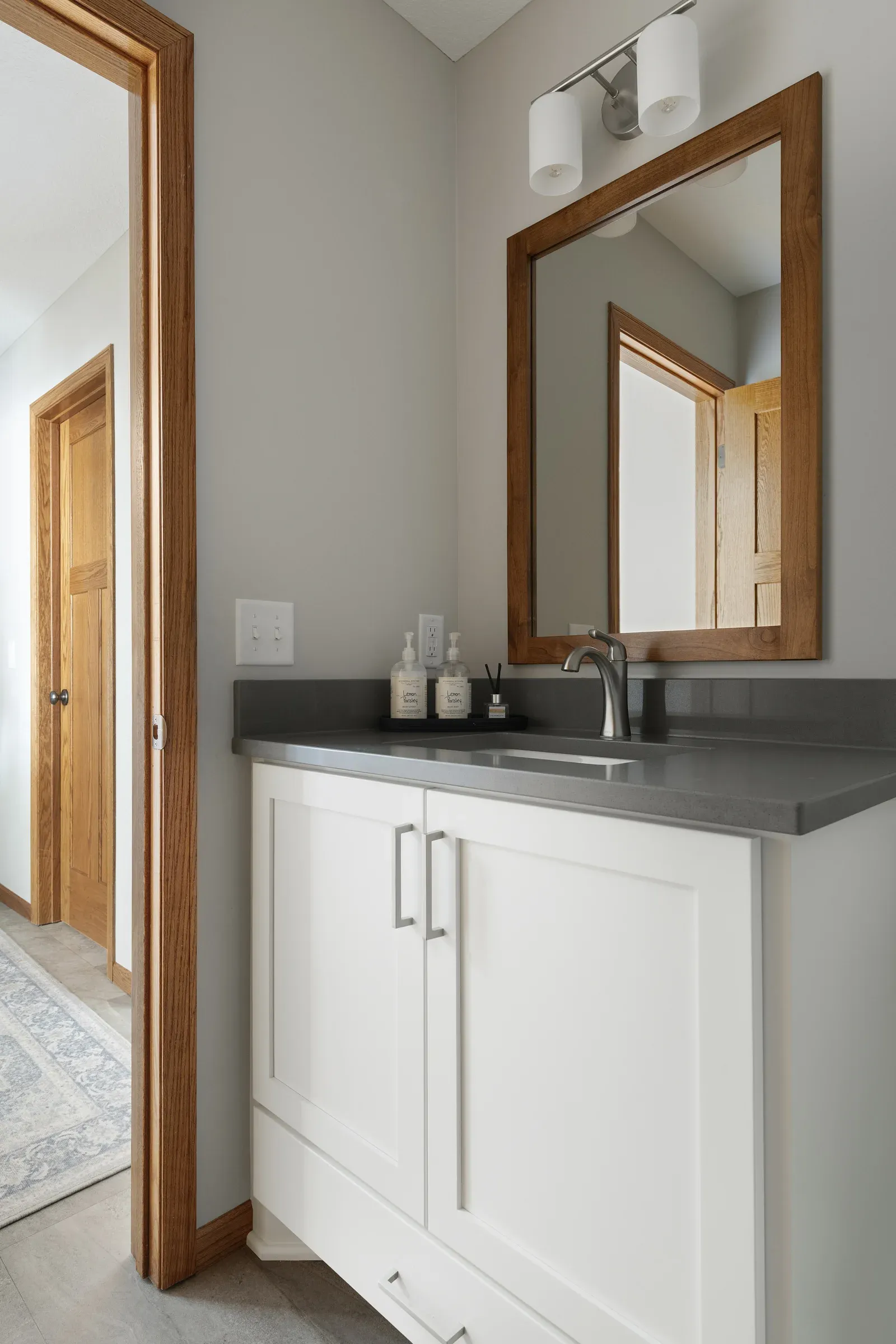 Powder bath vanity refresh with white cabinet, gray countertop, and wood-framed mirror – Elko New Market main-level remodel