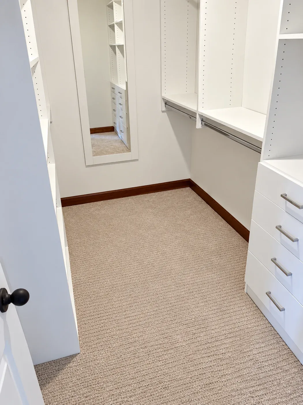 A full-length mirror on the end wall of a small walk-in closet in Apple Valley, with hanging rods and a drawer stack along the side walls